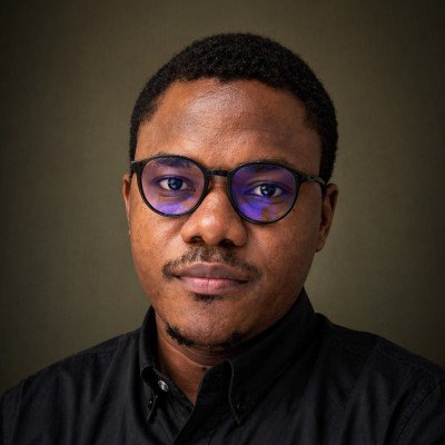 Anthony Ogunleye, wearing glasses and a black shirt